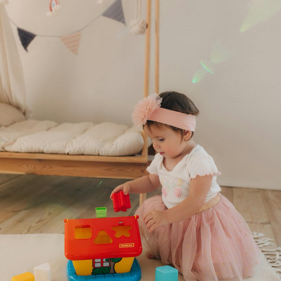 Ein junges Mädchen hat in einer gemütlichen Inneneinrichtung Freude an einem bunten Formsortierspielzeug.